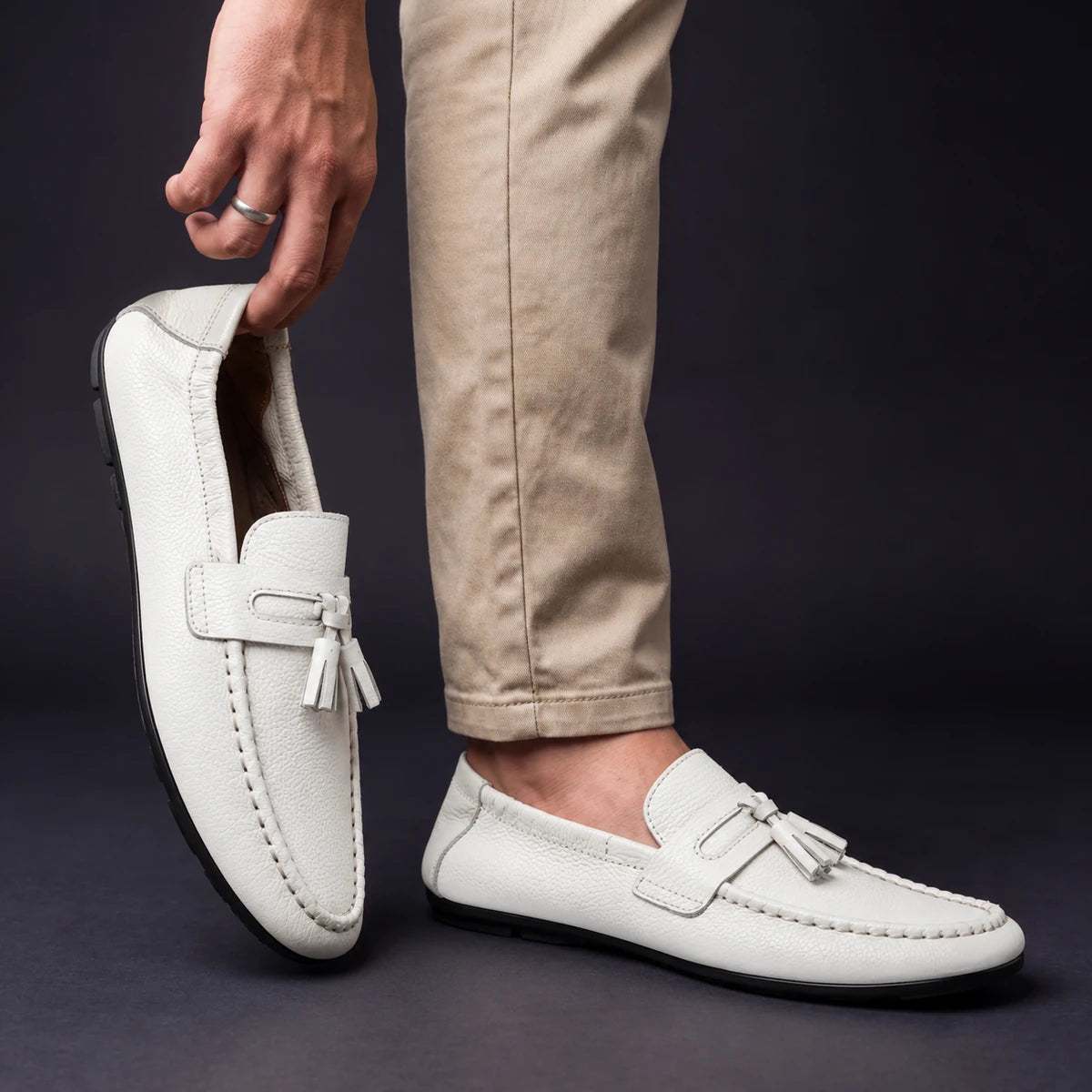 Cowhide Leather Loafers | Viggo White model holding shoe by heel opening beside matching worn shoe
