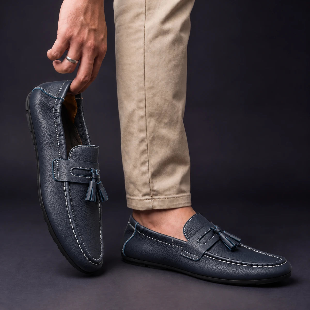 Cowhide Leather Loafers | Viggo Blue model holding shoe by heel opening beside matching worn shoe